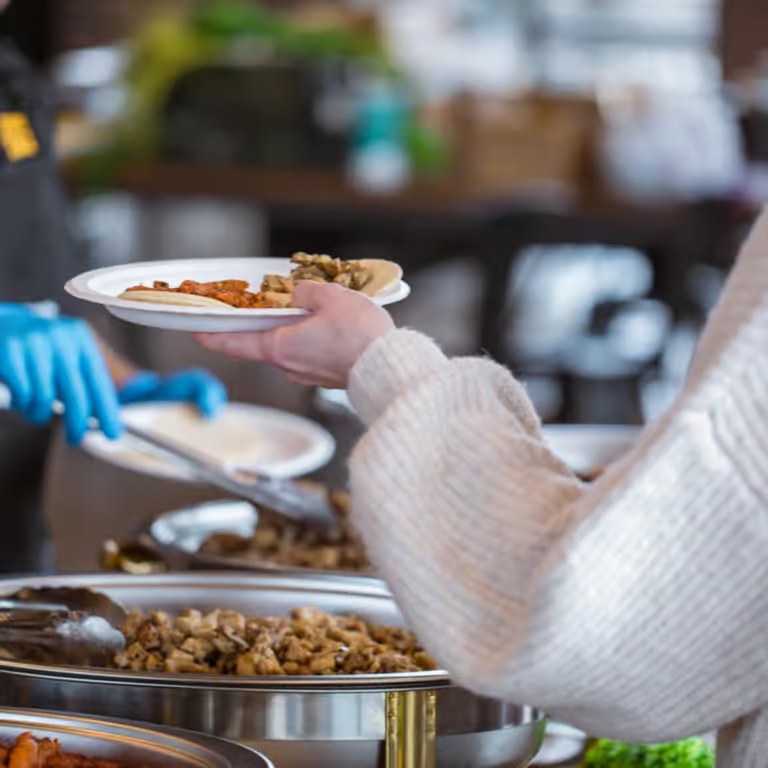 Guest being served fresh tacos from chafing dishes at a Jurassic Tacos catered event
